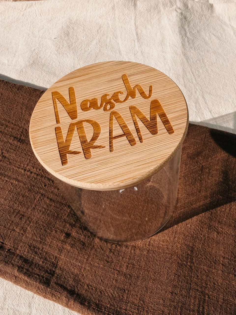 Vorratsglas mit einem Bambusdeckel und der Gravur „Naschkram“